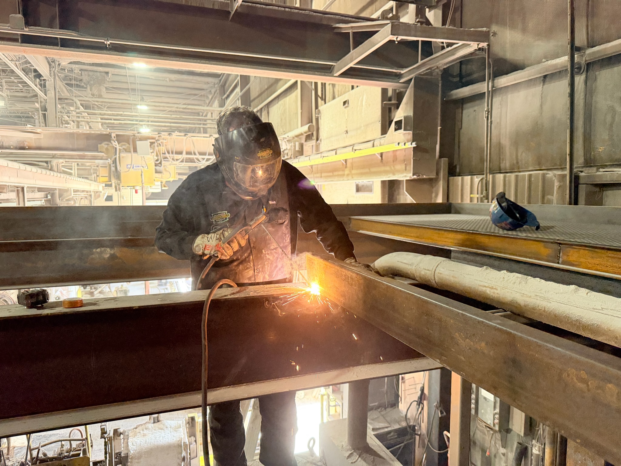 Schumacher Machine Repair welder fabricating an overhead structural steel beam on site.